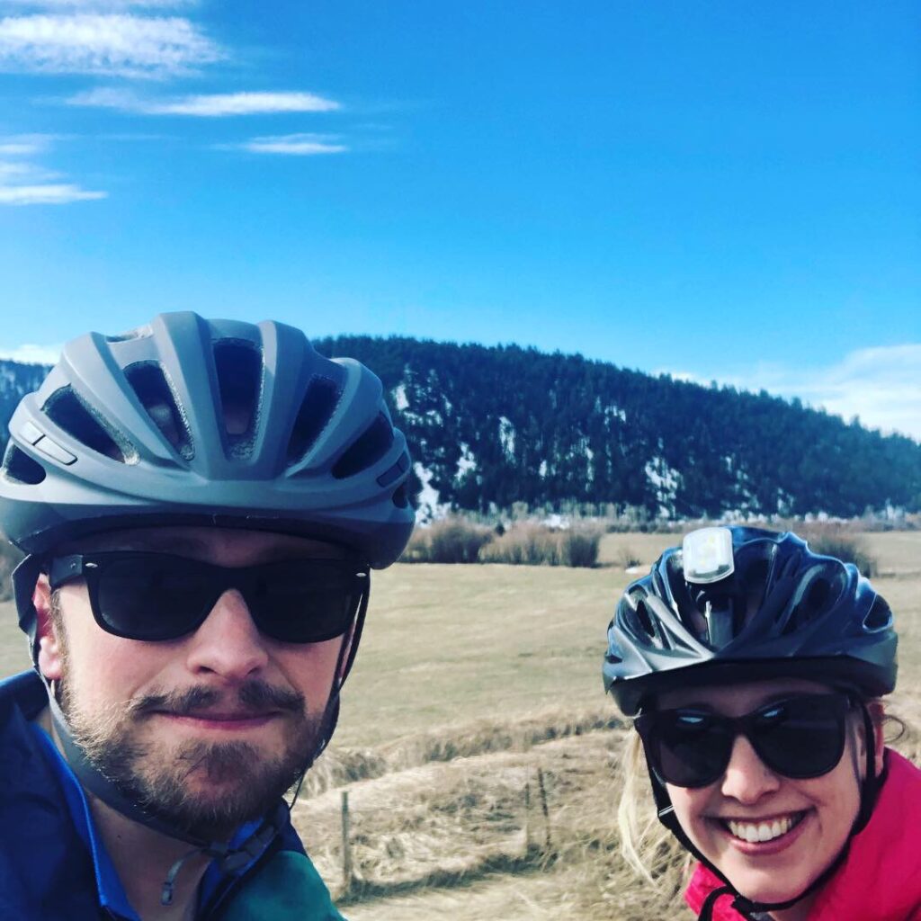 My wife and I biking in front of a hill.